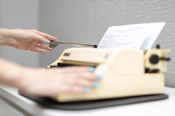 woman typing on a typewriter presses the carriage return lever