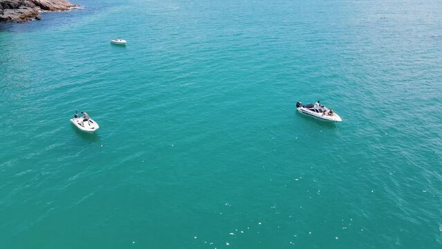 Aerial drone image of yacht boat at high speed in turquoise high seas boat ride on the beach people fanning florianópolis