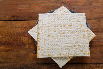 Matzah in a plate on a wooden table save a place.