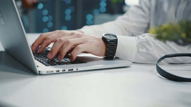 Footage of hands of young Caucasian man sitting at desktop, typing on keyboard. Business people concept. Working day. Shooting of black prestigious men's wrist watch. Blurred background of office