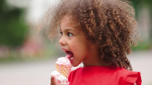 a black child eats ice cream in a waffle cone at a hot summer day