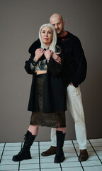 Vertical full length studio portrait of mature Caucasian man and woman in love wearing fashionable...