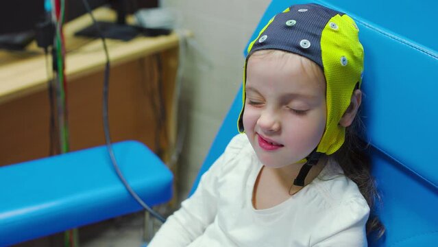 The girl smiles while doctor doing an electroencephalogram
