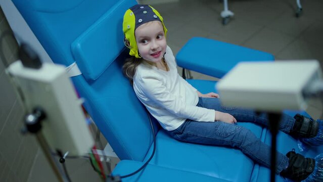 The girl smiles while doctor doing an electroencephalogram