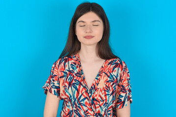 young caucasian woman wearing floral dress over blue background nice-looking sweet charming cute attractive lovely winsome sweet peaceful closed eyes