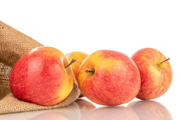 Four juicy organic apples with a jute bag, close-up, isolated on a white background.