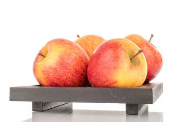 Four juicy organic apples on a black wooden tray, close-up, isolated on a white background.