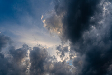 Naklejka na ściany i meble Dark gray clouds fly across the sky. Puffy fluffy grey clouds at spring day during sunset
