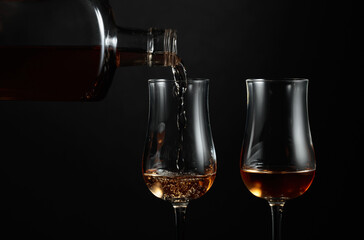 Strong alcohol drink is poured from a bottle into a glass.