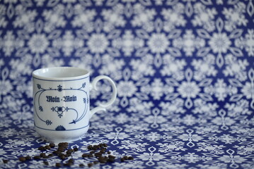 Kaffee in einer blau-weißen Tasse mit Kaffeebohnen