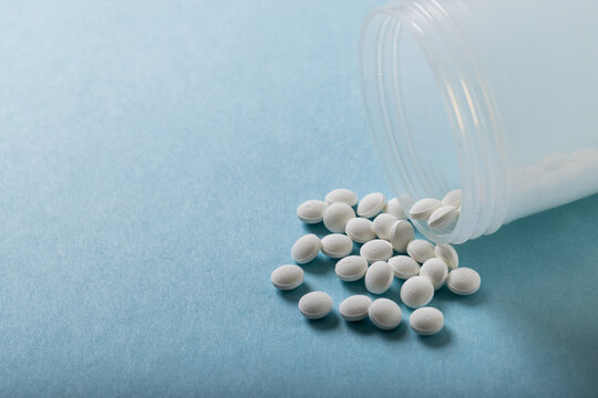 High Angle Close-up Of White Medicines Spilled From Bottle Over Blue Background, Copy Space