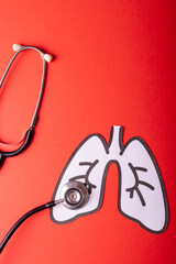 Overhead view of white paper lungs with stethoscope against red background, copy space