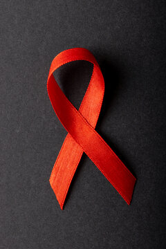 Overhead close-up of red aids awareness ribbon isolated against black background, copy space