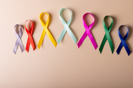 Directly above shot of various multicolored awareness ribbons arranged over peach background