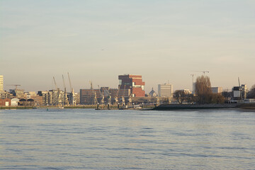 Antwerp skyline from across river Scheldt, with MAS museum, old industrial cranes and new residential skyscrapers in warm evening light

