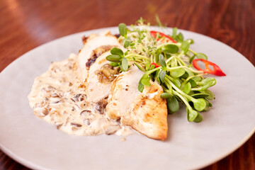 pieces of chicken roll with sauce and microgreens