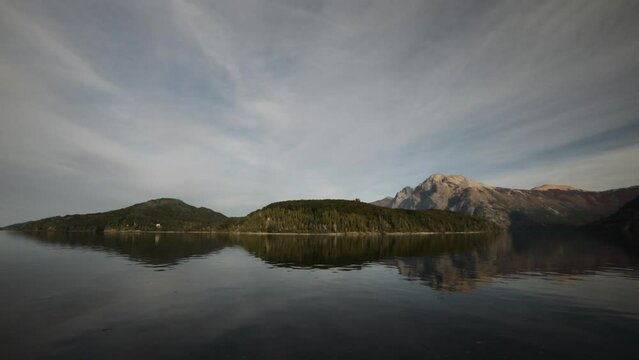 Sailing Nahuel Huapi lake in Bariloche, Patagonia. View from the boat. The mountains, sky and forest reflection in the water surface. 