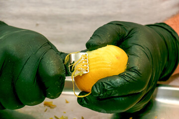 The process of preparing an alcoholic drink Limoncello at home. Male hands in black gloves peel the...