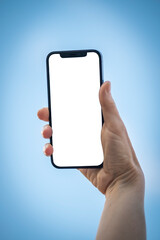 Hand holding phone with blank screen on blue background concept
