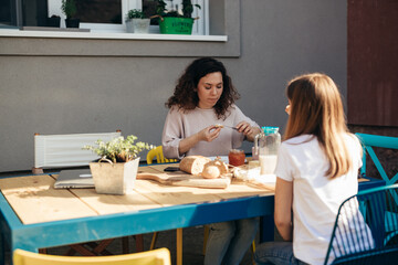 Obraz na płótnie Canvas mother and daughter having breakfast in home backyard