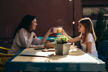 mother and daughter cheers during breakfast in backyard