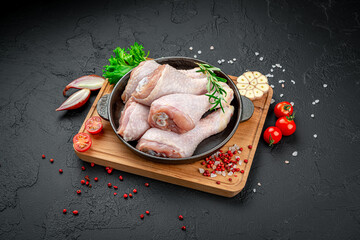 Fresh chicken drumsticks, legs with ingredients for cooking in a frying pan.