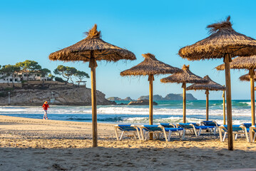 deserted morning sea beach with sunny screens. Platja Palmira