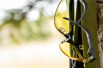 Tactical military glasses on the tree. Close up view. Sport (tactical) glasses with reflective surface. SWAT equipment. Military protection. Hunting background.