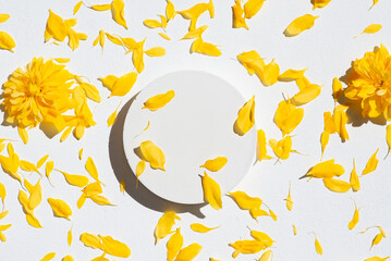 White podium for product presentation on yellow flower petals background.