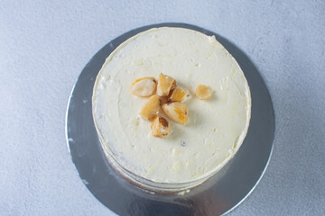 3-tier cake with walnuts and vanilla cream on gray background