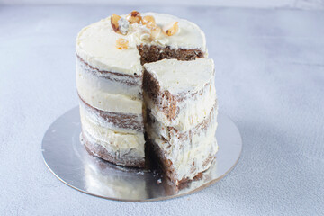 3-tier cake with walnuts and vanilla cream on gray background