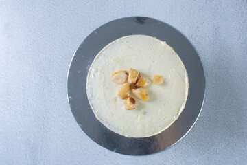 3-tier cake with walnuts and vanilla cream on gray background
