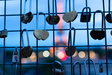 Illuminated Eiffel Tower is seen at night behind fence filled with locks and lockers with heart...