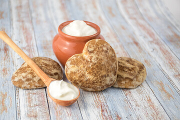 Beautiful heart-shaped gingerbread cookies are arranged with sour cream. Delicious cookies with spikelets
