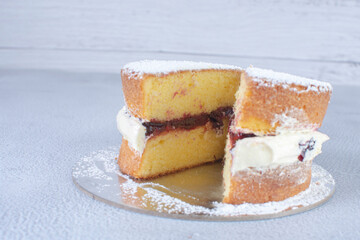 Traditional vanilla cake with blackberry sauce and powdered sugar on a gray background