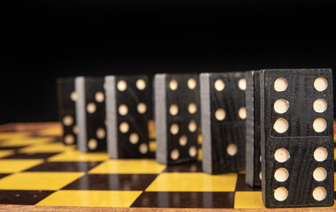 Dominoes, old domino pieces lined up on a board, dark background, selective focus on the first...