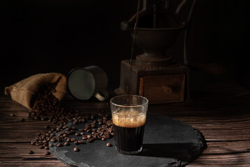 Coffee, cup with coffee and coffee beans on a gray stone over wood, dark food style photo, selective focus.