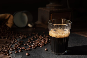 Coffee, cup with coffee and coffee beans on a gray stone over wood, dark food style photo, selective focus.