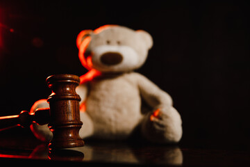 Judge gavel and bear in a dark court room. Law and children concept