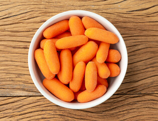 Baby carrots in a bowl over wooden table