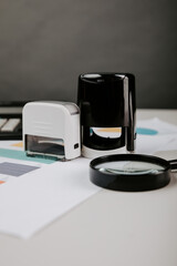 Office desktop with documentsm magnifier and stamp close-up. Vertical image