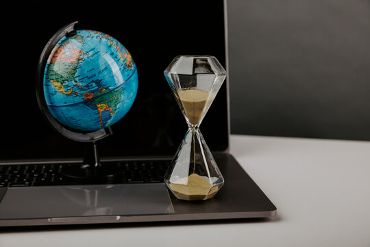 World globe with laptop and hourglass. Online business and globalisation theme