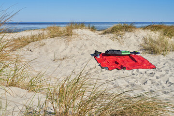 a red blanket is lying in the sand of the dunes at the North Sea