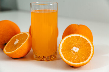 Fresh juice with ripe oranges in a glass on a white background. Oranges cut into slices. Vitamin juice, a healthy lifestyle. Vegetarianism, vegan, diet, fruit, nectar. Homemade juice, drink.