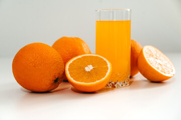 Fresh juice with ripe oranges in a glass on a white background. Oranges cut into slices. Vitamin juice, a healthy lifestyle. Vegetarianism, vegan, diet, fruit, nectar. Homemade juice, drink.