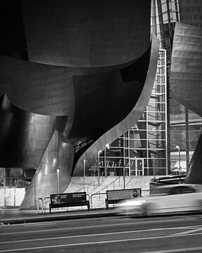 LOS ANGELES, CA, SEP 2021: motion-blurred car speeds past the Walt Disney Concert Hall in Downtown at night. Black and white