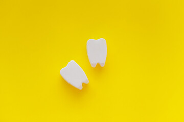 White plastic teeth shapes isolated on yellow background, representing dental care concept, teeth alignment with braces abstract.