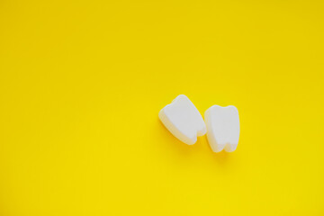 White plastic teeth shapes isolated on yellow background, representing dental care concept, teeth alignment with braces abstract.