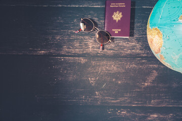 World map and items on wooden background, flat lay. summer travel copy space for text. map, sunglasses, passport, phone, pen,mask, book on wooden background top view. planning vacation concept.
