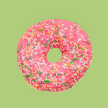 Pink glazed donut with multicolored sprinkles on green background. Sweet food, diet concept